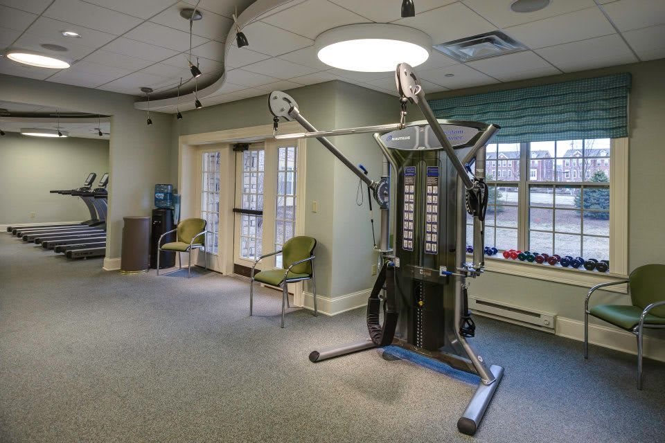 A well-lit fitness room featuring exercise equipment and seating.