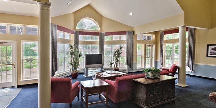 A spacious living room with large windows and vaulted ceilings, featuring comfortable seating and plenty of natural light.