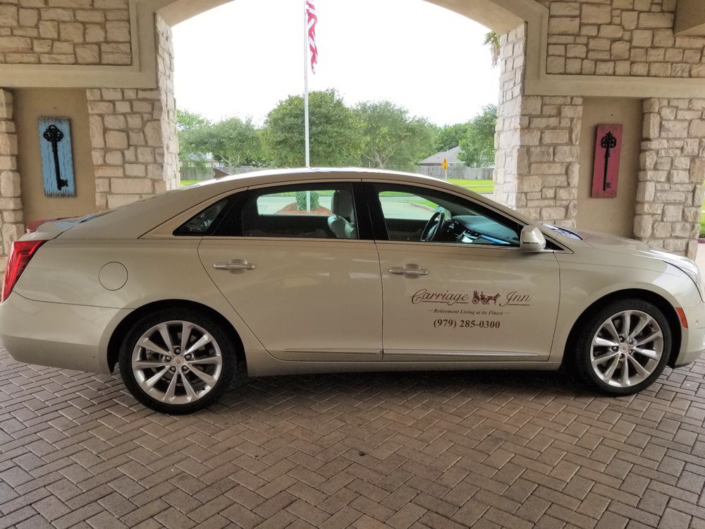 A beige sedan parked under a covered building entrance.