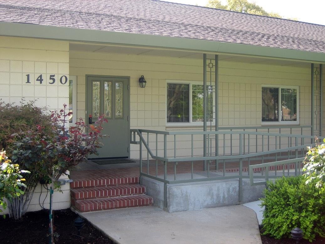 A quaint house entrance with a green door and brick steps leading to a small porch.