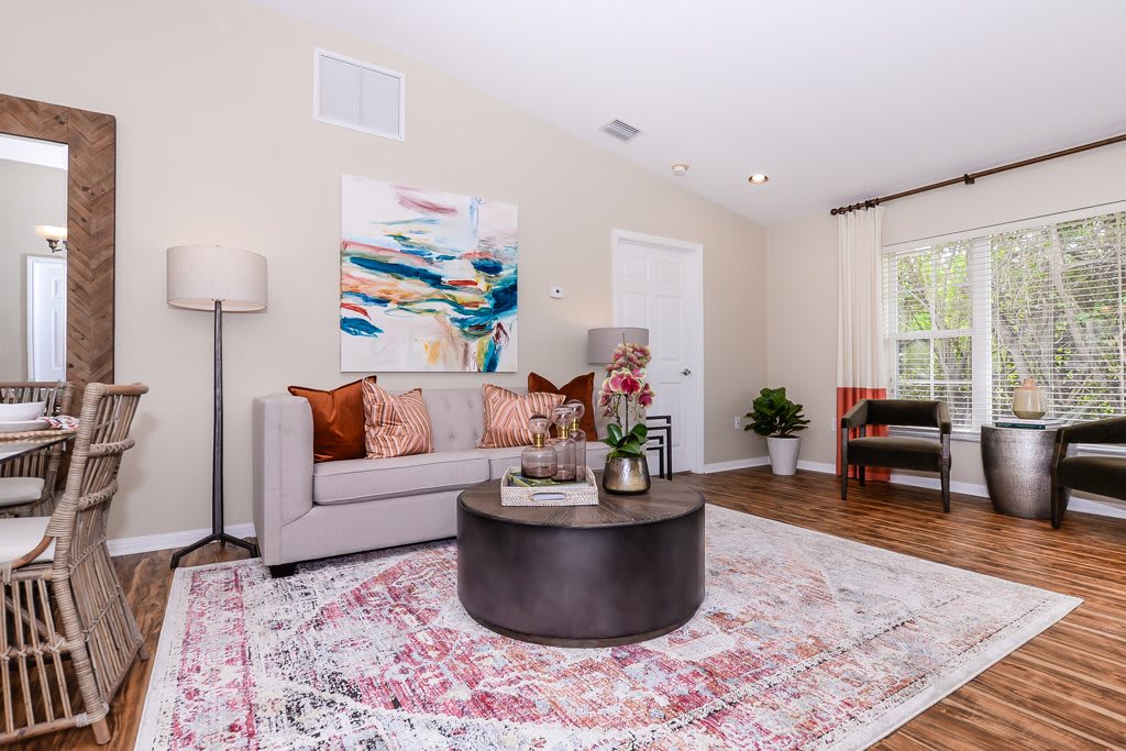 A cozy living room with a modern sofa, colorful artwork, and a round coffee table on a patterned rug.