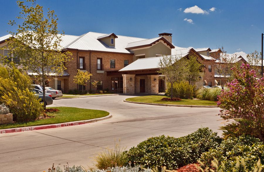 A modern residential building with a landscaped driveway.