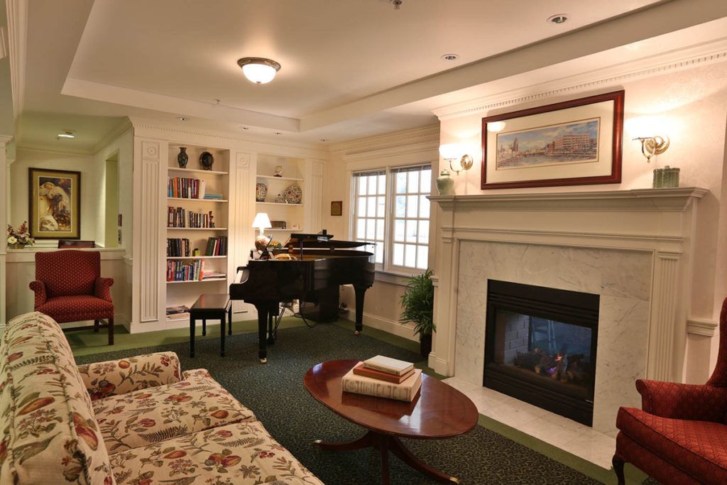 A cozy living room featuring a fireplace, grand piano, and bookshelves.