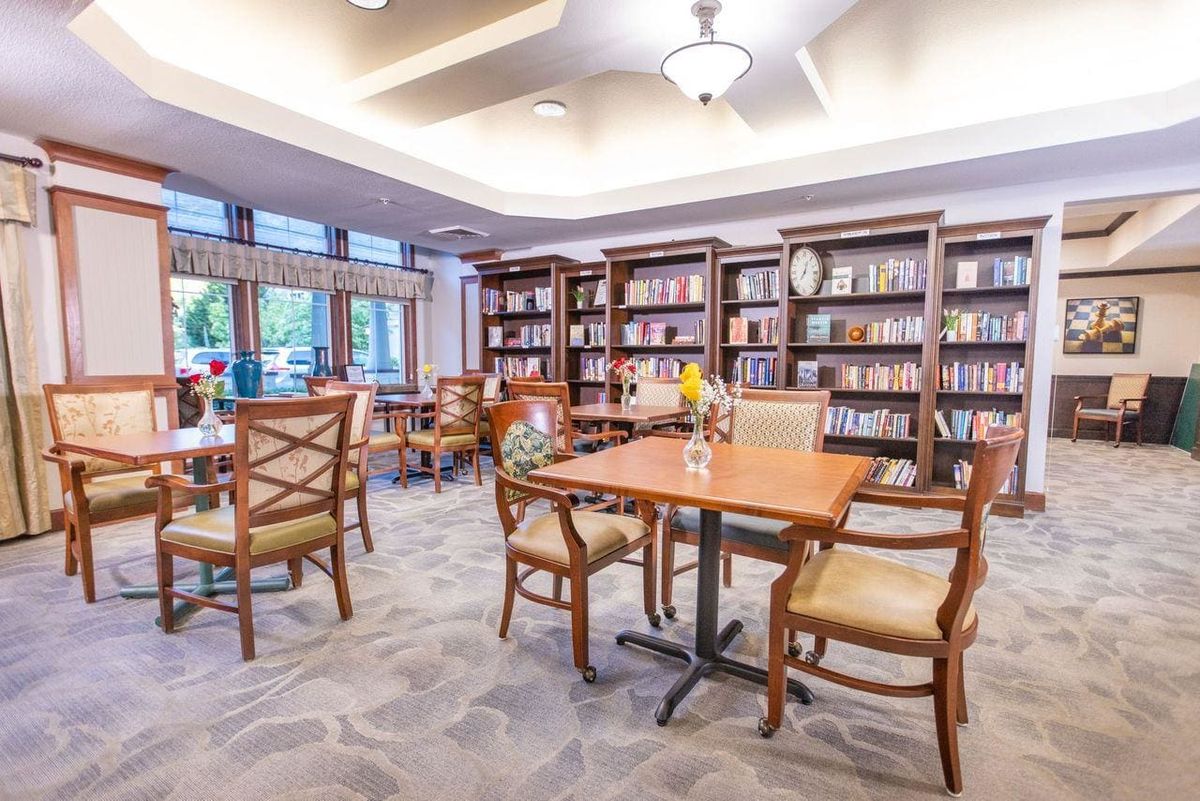 A cozy library with bookshelves, tables, and chairs set up for reading.