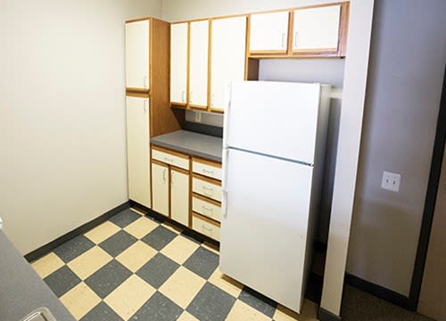 A retro-style kitchen with checkered flooring and white cabinets.