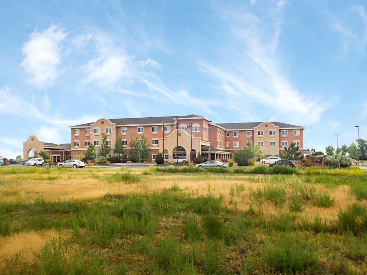A large hotel building set against a blue sky with grassy foreground.