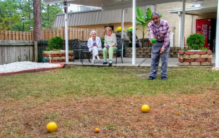 A group of seniors enjoying a leisurely game of bocce in the yard.