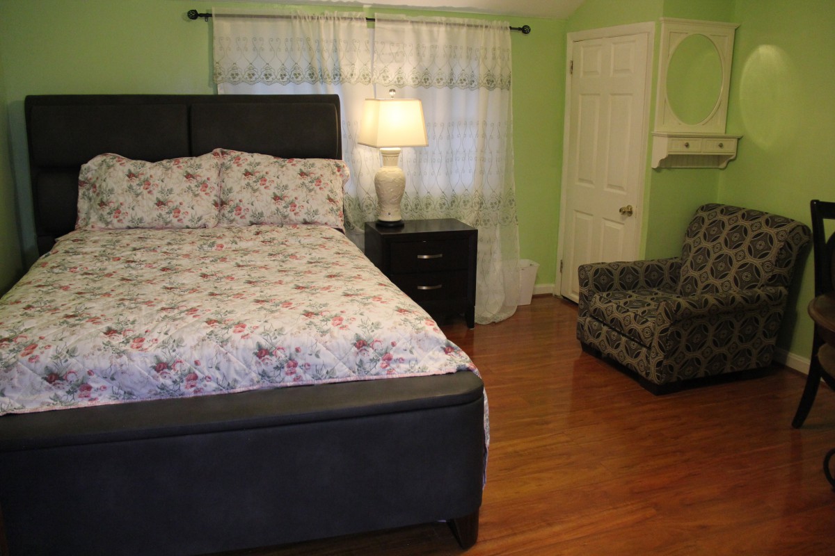 A cozy bedroom with a bed, nightstand, and armchair.