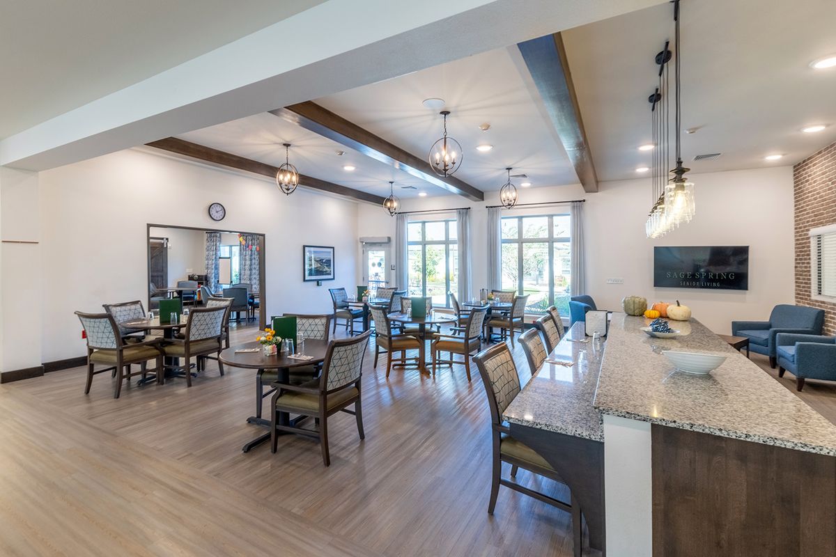 A spacious dining area with multiple tables and chairs, featuring large windows and elegant lighting.