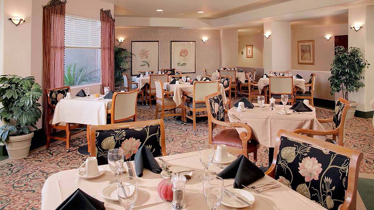 A spacious and elegantly set dining room in a restaurant, featuring neatly arranged tables and chairs.