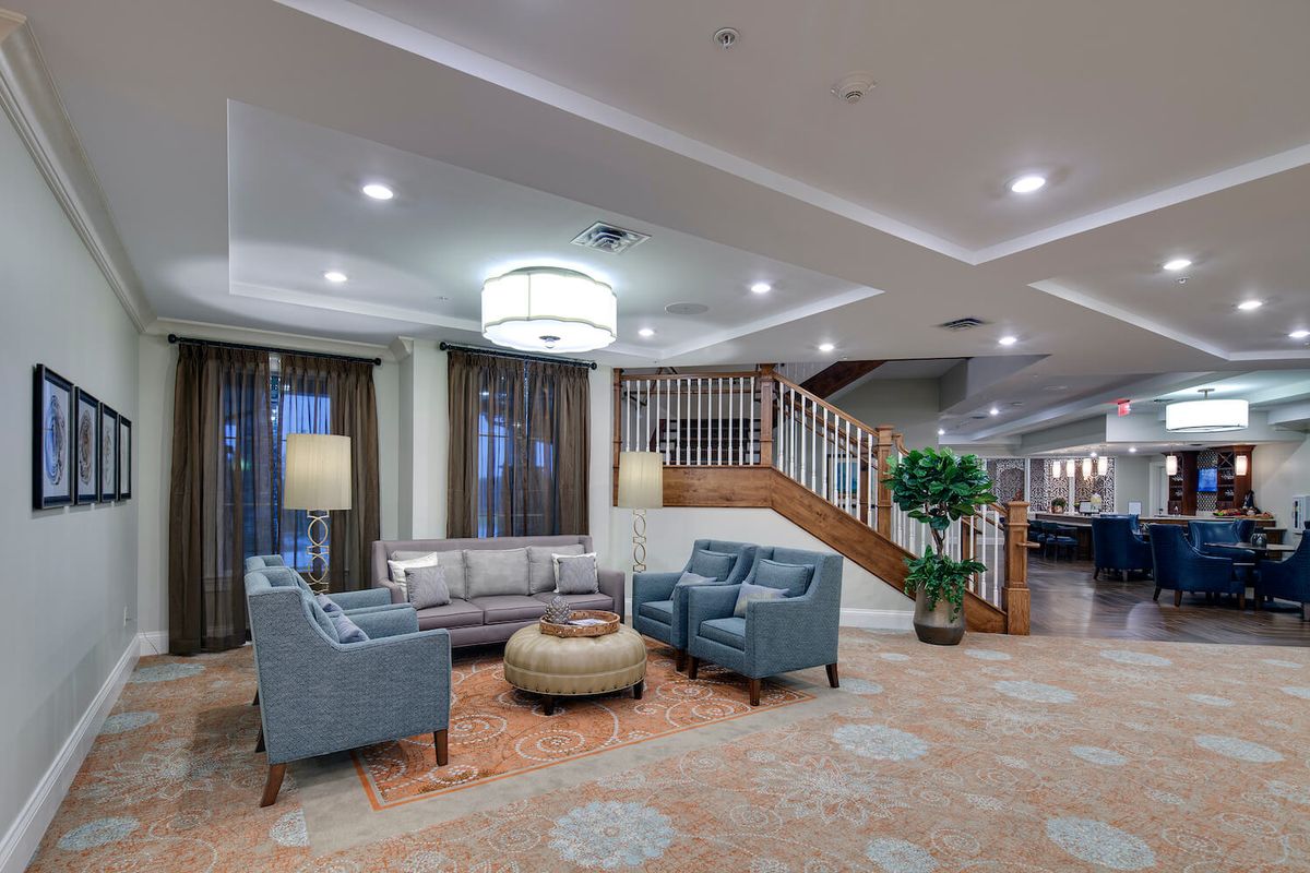 A cozy lobby area featuring comfortable seating, elegant lighting, and a staircase leading to an upper floor.