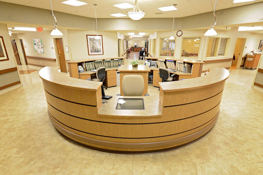 A modern hospital reception area with a wooden front desk and comfortable seating.