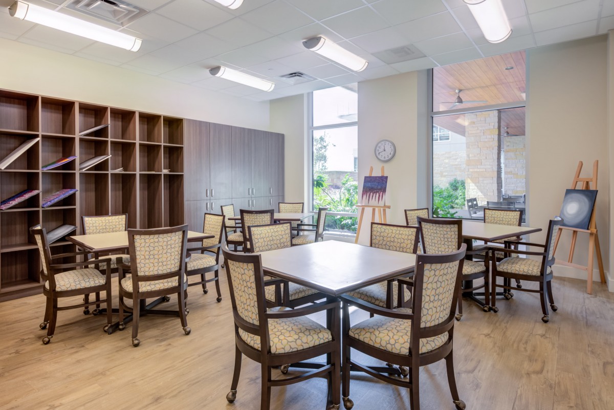 A modern dining area with multiple tables and chairs, well-lit by overhead lights.