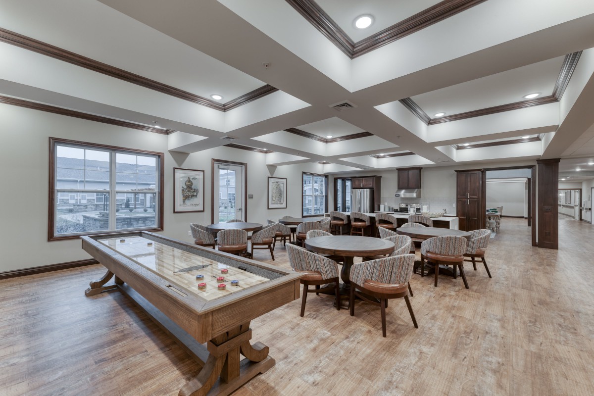 A modern game room featuring a shuffleboard table and seating area.