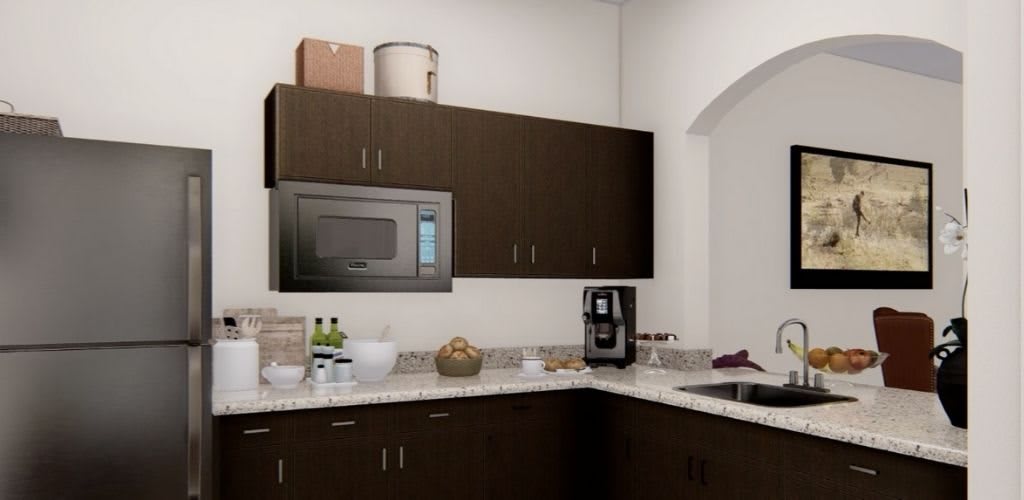 A modern kitchen with dark cabinets, featuring a microwave and coffee maker on the countertop.