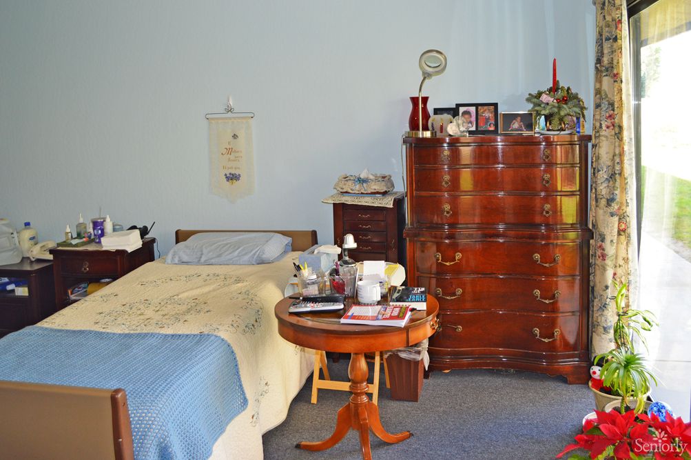 A cozy bedroom with a single bed, a wooden dresser, and a round table.