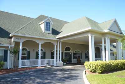 A large house with a covered porch and driveway, featuring traditional architecture.