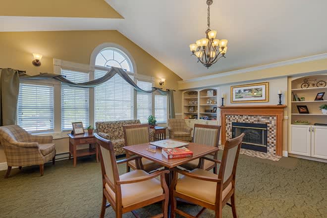 A cozy living room with a chandelier, fireplace, and a wooden table surrounded by chairs.