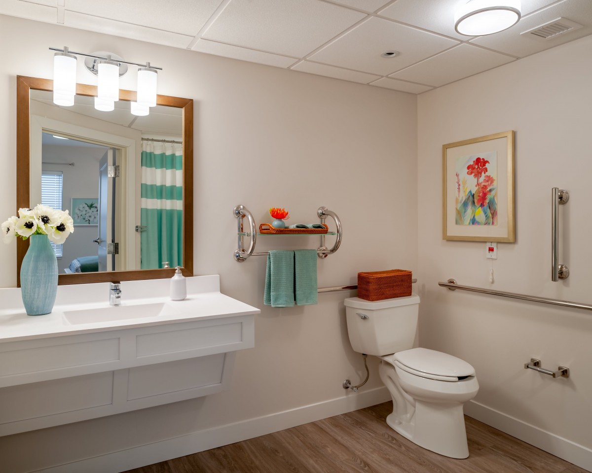 A modern bathroom featuring a clean design with a toilet, sink, and mirror, complemented by wall art and decorative towels.