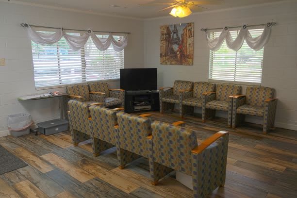 An empty waiting room with patterned chairs and a television.