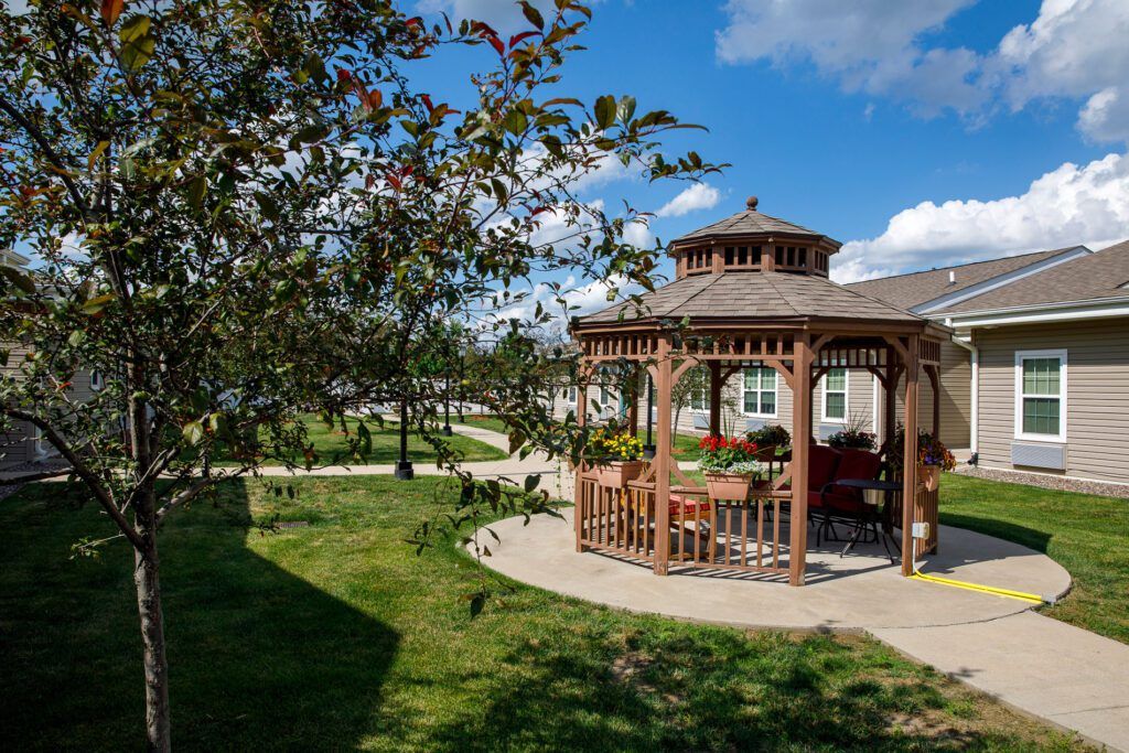 A picturesque gazebo in a lush garden setting under a clear blue sky.