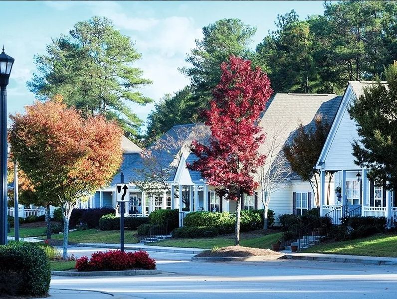 A picturesque suburban neighborhood with charming houses and vibrant autumn foliage lining the street.