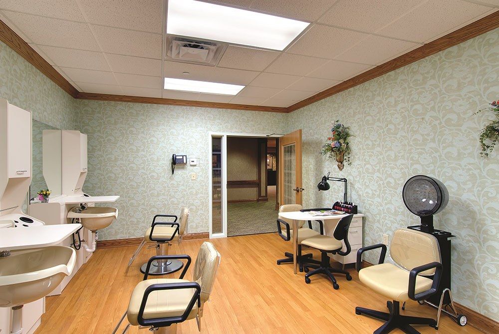 An empty salon with chairs and workstations, well-lit and featuring wooden flooring.