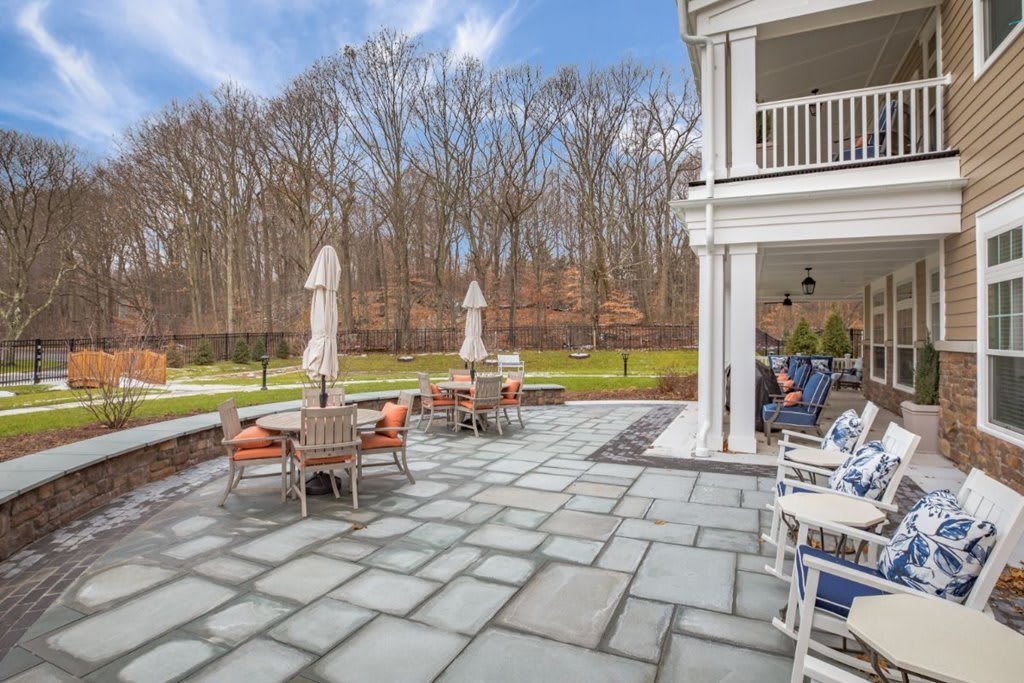 Spacious outdoor patio with seating and umbrellas overlooking a wooded area.