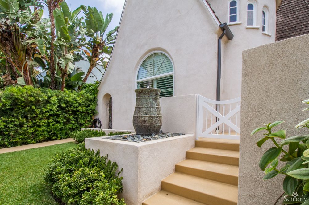 A charming house exterior with a garden, staircase, and decorative features.