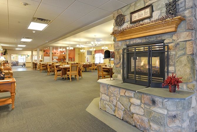 A cozy restaurant interior featuring a stone fireplace and wooden tables and chairs.