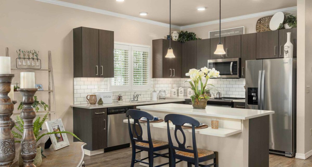 A modern kitchen interior with dark cabinets, white countertops, and stylish pendant lights.