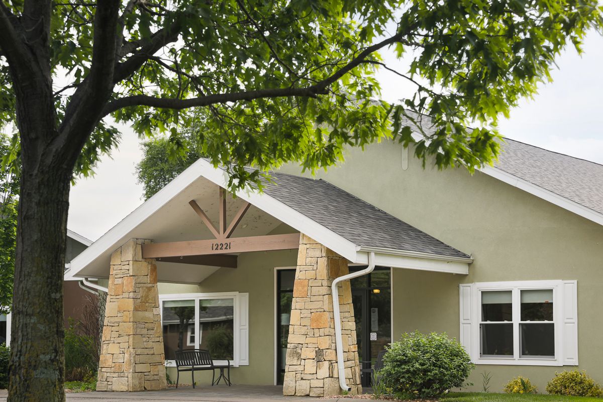 A quaint residential building with a front entrance and surrounding greenery.