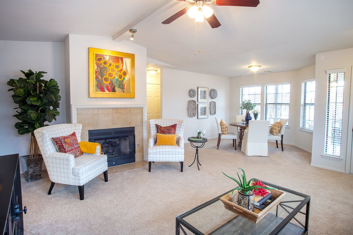 A modern living room with comfortable seating, a fireplace, and a dining area in the background.