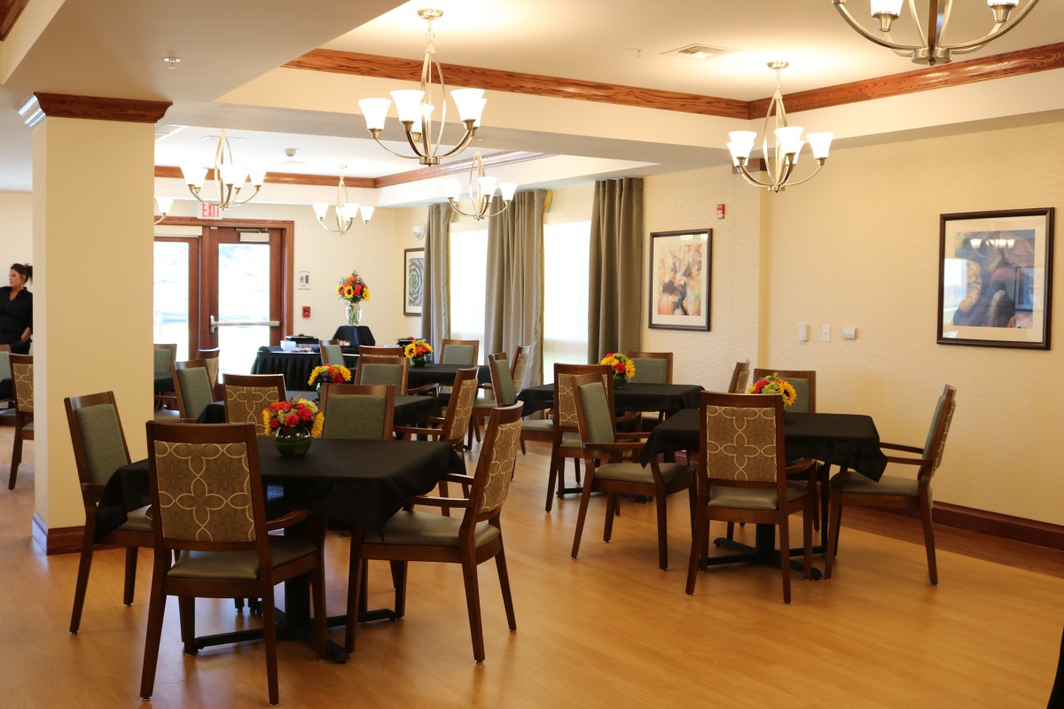 A well-lit dining area featuring several tables and chairs, adorned with chandeliers and tasteful decorations.
