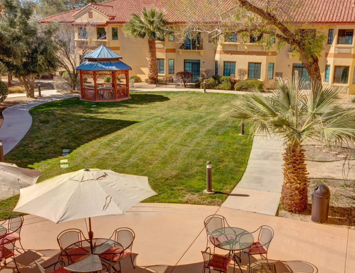 A peaceful courtyard with a gazebo, surrounded by buildings and outdoor seating under umbrellas.