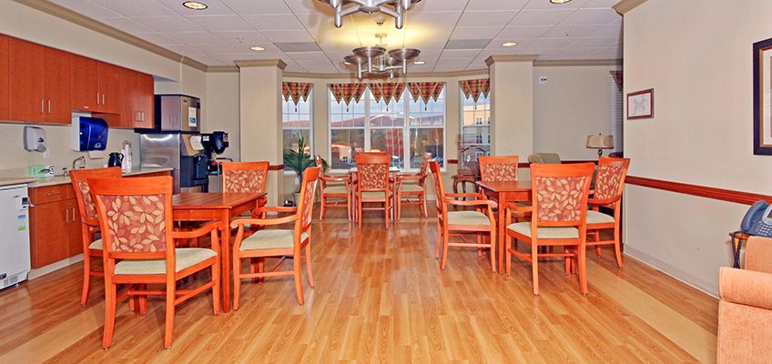 A brightly decorated dining area with orange chairs and wooden flooring.