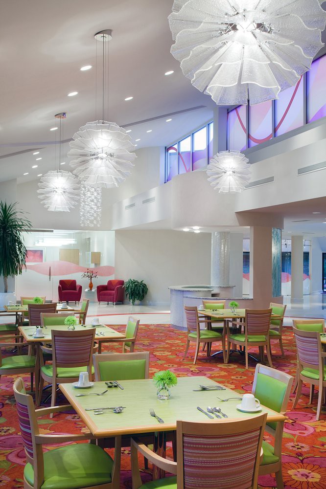 Modern dining area with green-accented tables and stylish lighting fixtures.