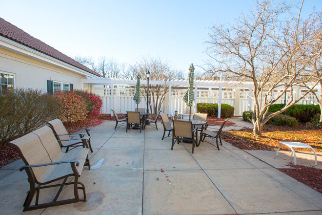 An outdoor patio with chairs and tables set under a clear blue sky.