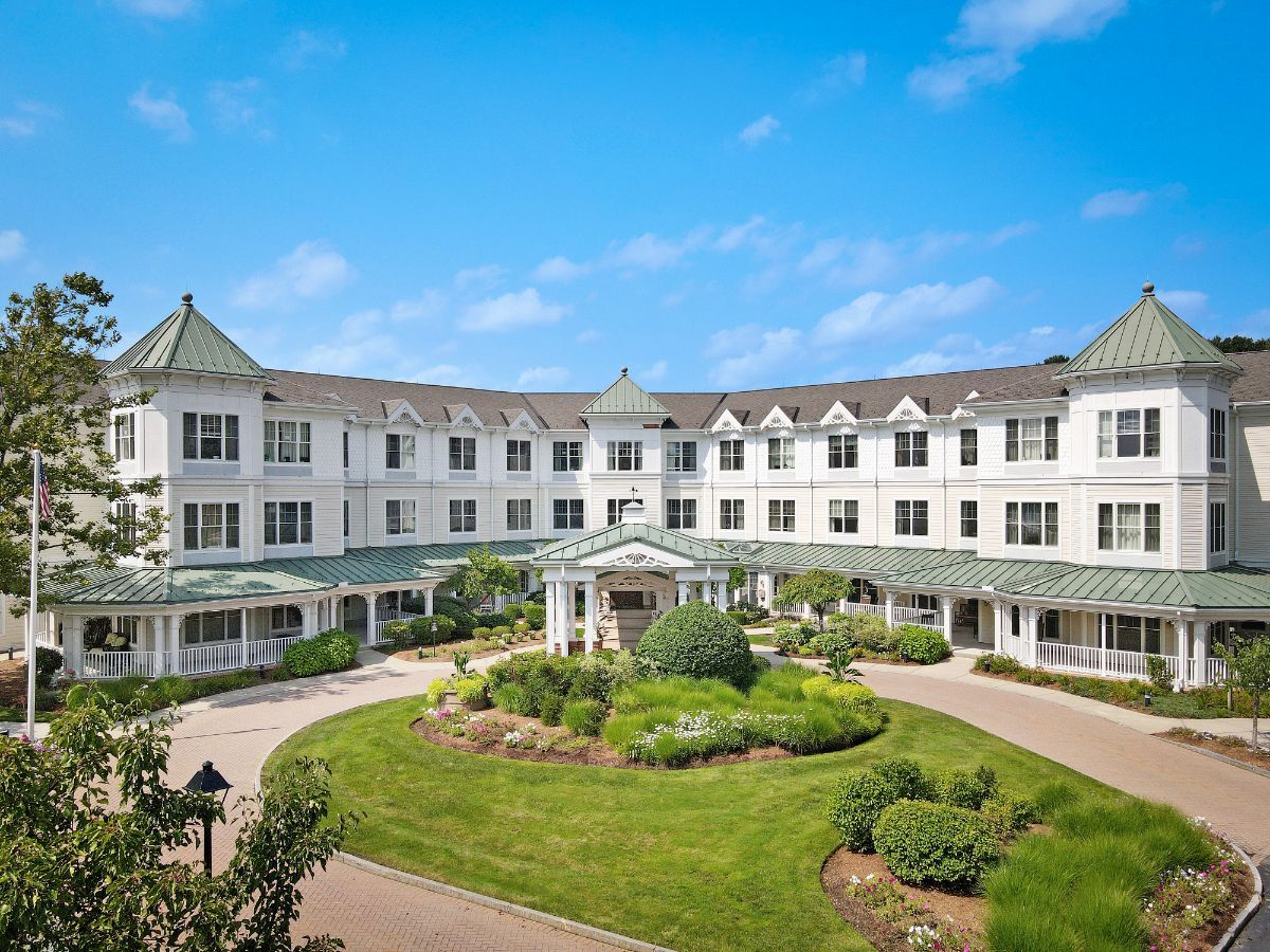 A large residential building with a well-maintained garden and clear blue sky.