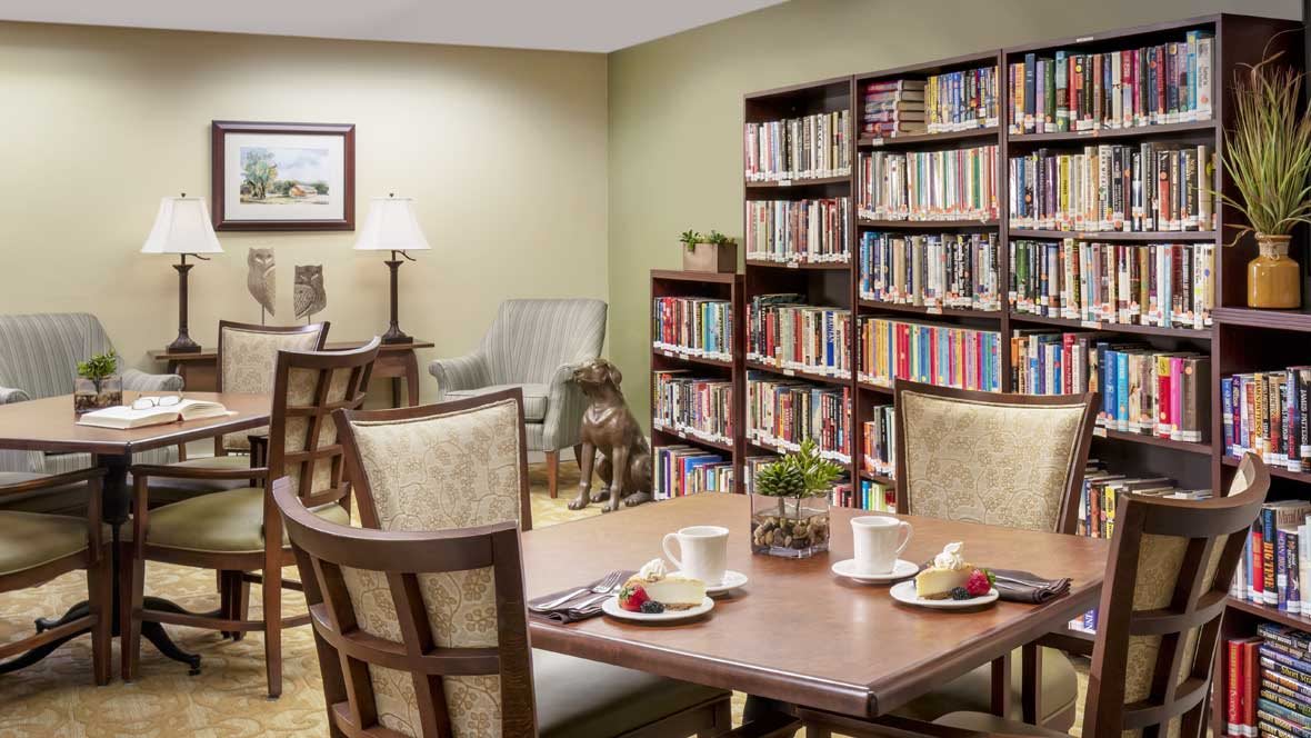 A cozy library reading area with bookshelves, a table, and chairs.