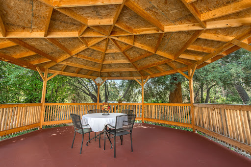 A cozy wooden gazebo featuring a round table and chairs, perfect for enjoying the outdoors.