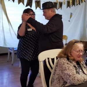 A joyful moment shared between two dancers at a social event, with another guest enjoying the atmosphere.