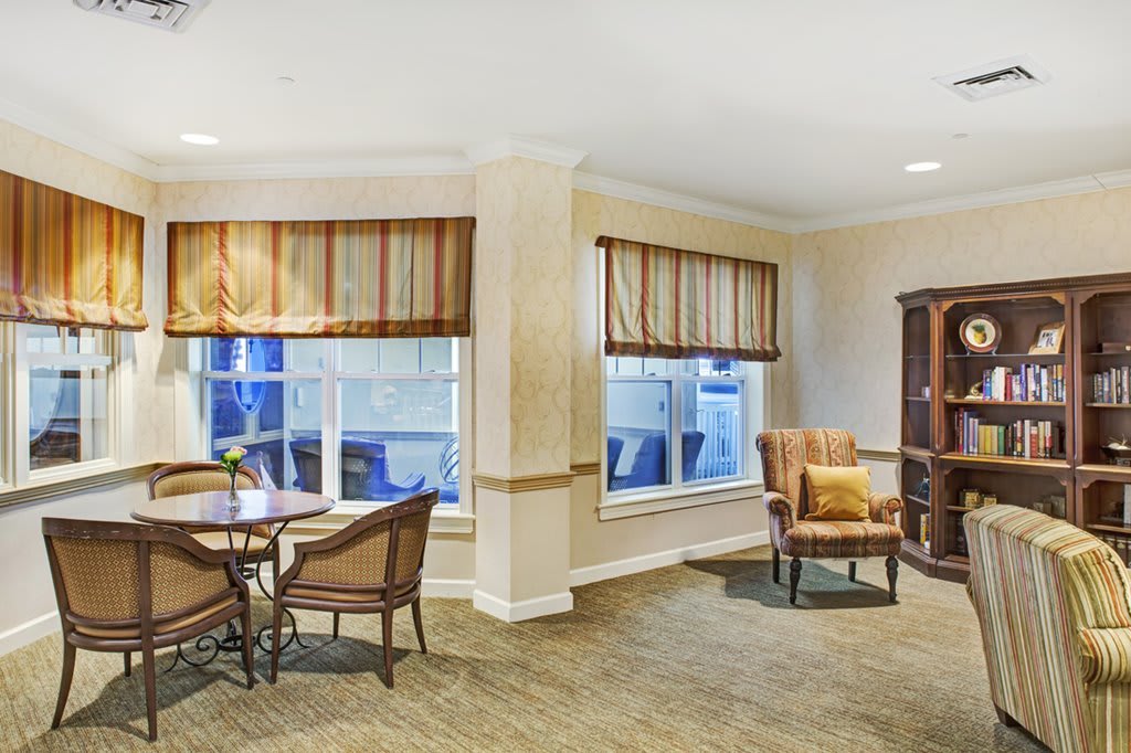 A cozy living room with chairs, a small table, and large windows.