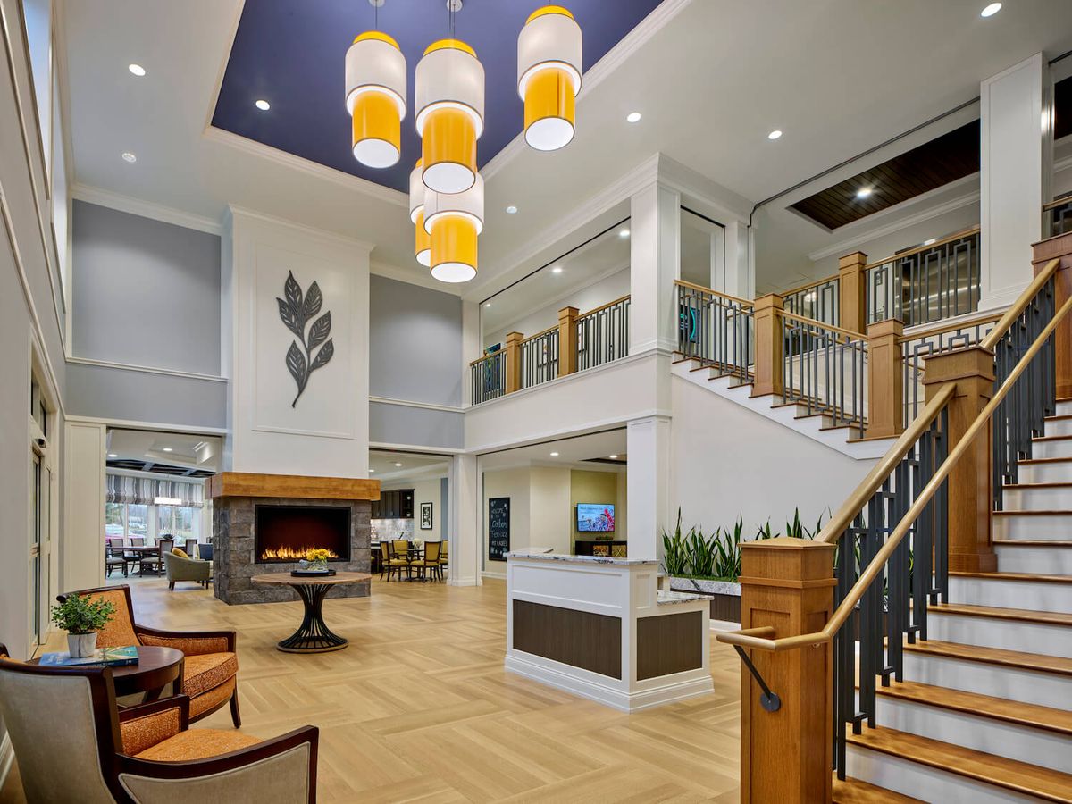 A modern lobby with elegant lighting, comfortable seating, and a grand staircase.