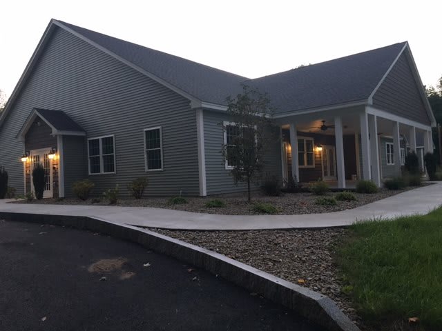 A single-story residential building with a sloped roof and landscaped front yard.