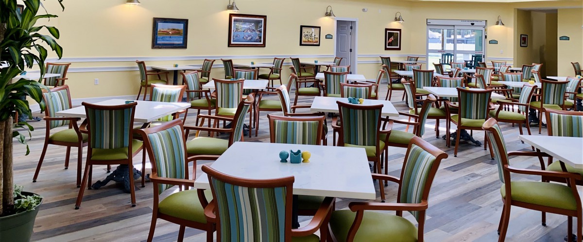 An empty dining room with neatly arranged tables and chairs, decorated with framed artwork on the walls.