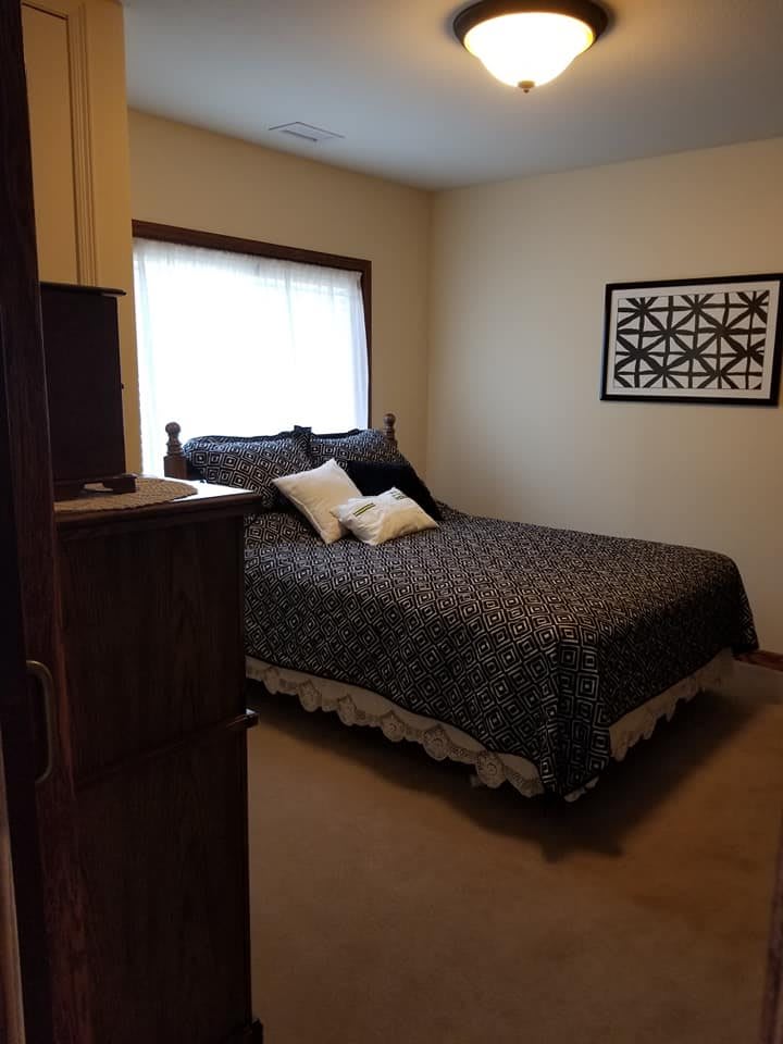 A cozy bedroom with a neatly made bed, adorned with decorative pillows and art on the wall.