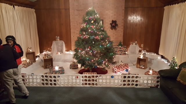 A beautifully decorated Christmas tree surrounded by holiday lights and presents indoors.