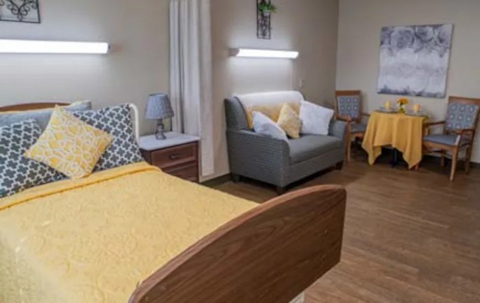 A cozy bedroom featuring a bed with yellow bedding, a sofa, and decorative accents.