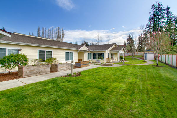 A modern house with a well-maintained lawn and landscaping under a clear blue sky.